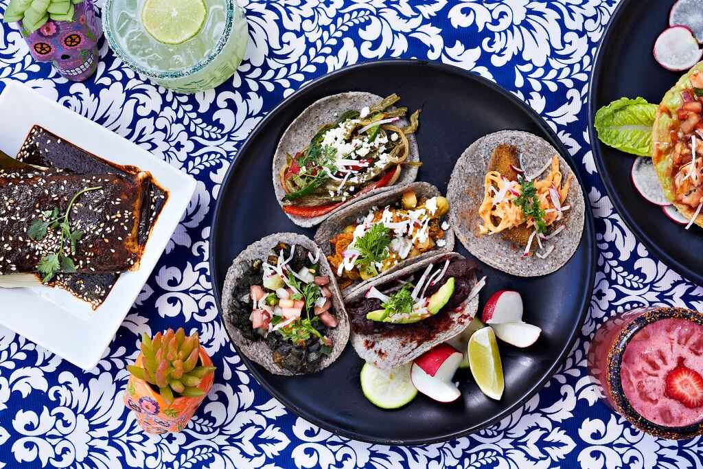 Tacos vegetarianos en el sentido de las agujas del reloj desde arriba a la izquierda: Nopales con Rajas (cactus y pimientos marinados al estilo escabeche con fresco de búsqueda), taco de calabacín, Jamaica Pastor (flor de hibisco salteada en pasta de achiote), Huitlacoche (trufa de maíz dulce mexicana) ), y centro: Flor de Calabaza (flor de calabaza salteada con aceite de oliva, cebolla, tomate y jalapeños). A la izquierda hay tamales de pollo con salsa roja fotografiados en DC Corazon en Washington, DC el 19 de junio de 2022 (Foto de Deb Lindsey para The Washington Post a través de Getty Images).