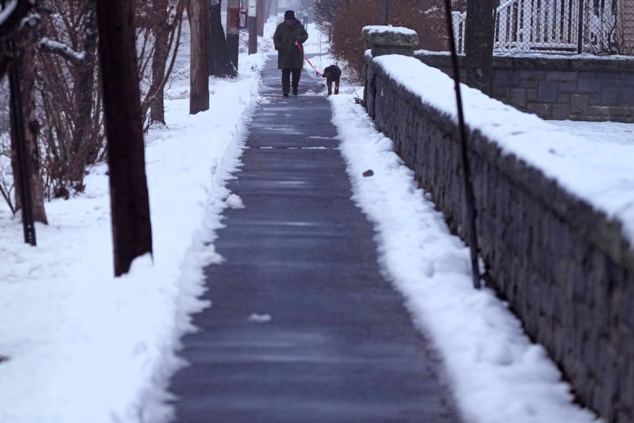 Un hombre pasea a un perro mientras cae una lluvia ligera durante una tormenta invernal, el miércoles 11 de diciembre de 2024, en Concord, Nueva Hampshire (Foto AP/Charles Krupa)