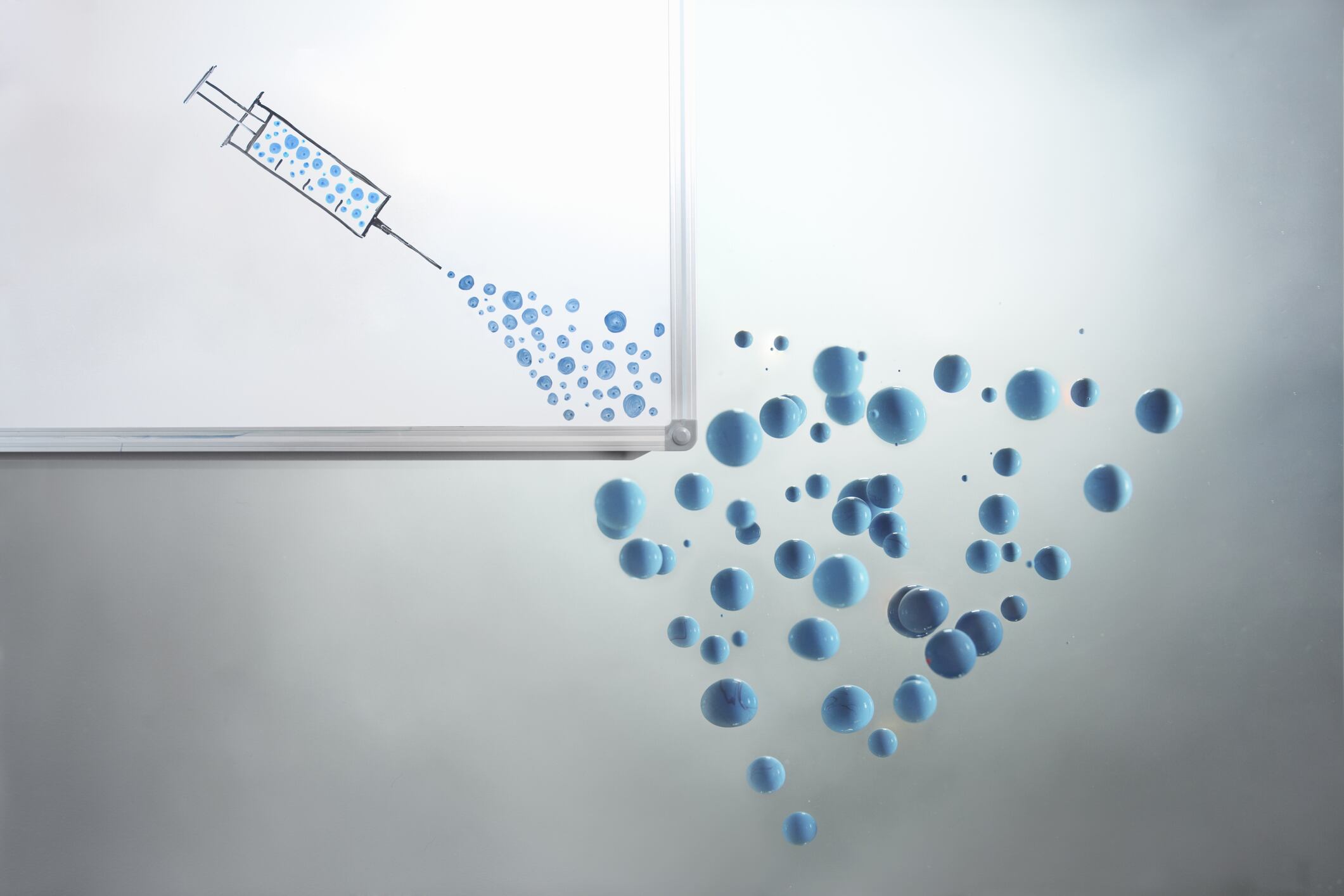 Puntos azules que emergen de una jeringa - Imagen de referencia