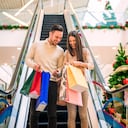 Romantic Christmas shopping.Sale, technology and people concept - happy young couple with shopping bags.Image taken inside a shopping mall.