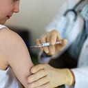 Niño recibiendo una vacuna contra la gripe en la clínica. Niño pequeño recibiendo una vacuna en su brazo por un pediatra con guantes.