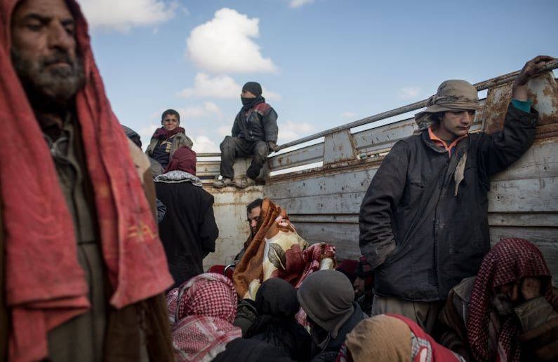 BAGOUZ, SIRIA - 11 DE FEBRERO: Los hombres y los niños que han huido luchando en Bagouz miran por la parte trasera de un camión después de detenerse en un punto en la carretera para que los miembros de la prensa puedan entrevistarlos antes de ser trasladados a un campamento. FOTO: Chris McGrath / Getty Images