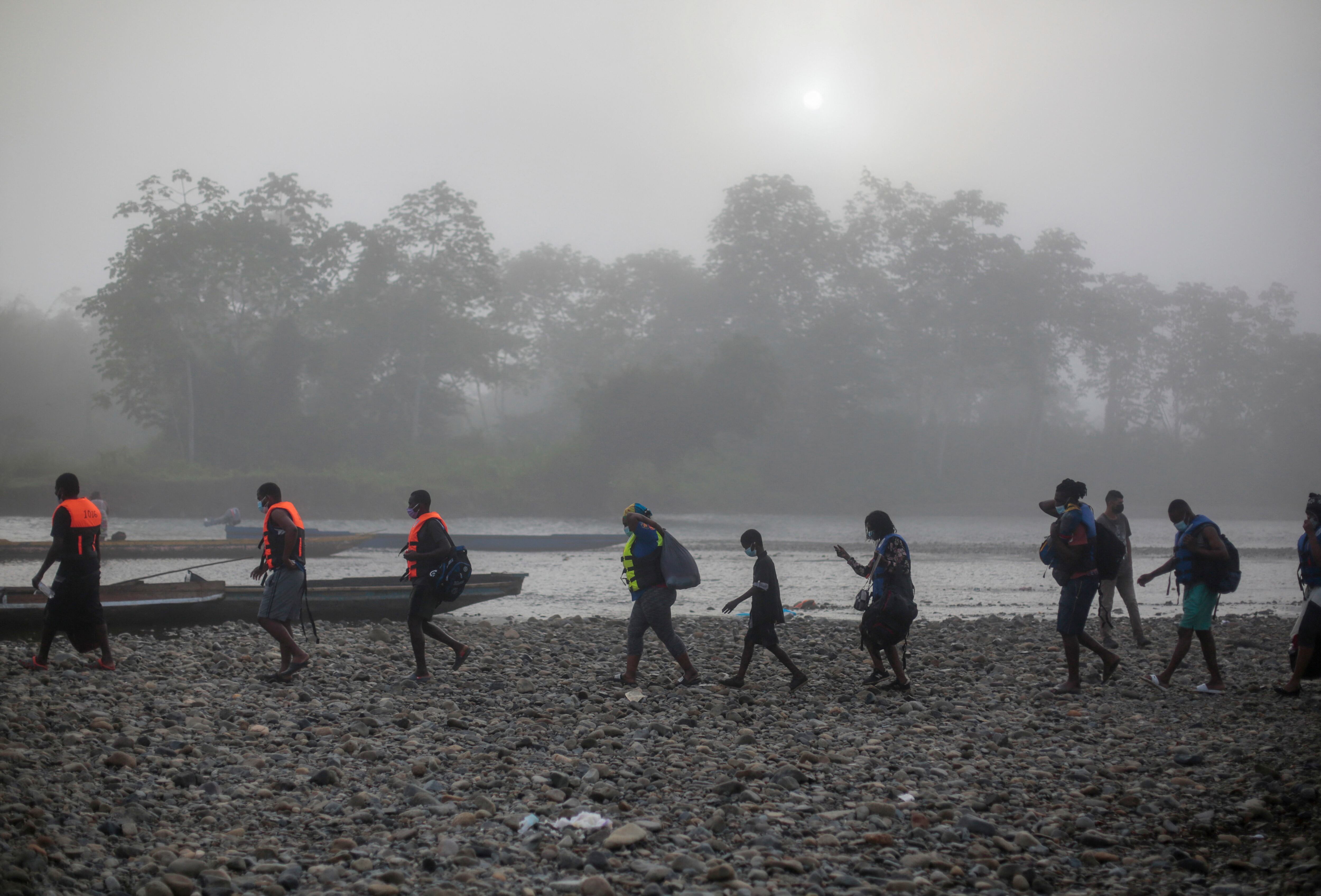 Los migrantes caminan hacia la embarcación donde serán transportados desde el poblado de Bajo Chiquito hasta la Estación de Recepción de Migrantes en Lajas Blancas, Provincia de Darién, en Panamá el 23 de agosto de 2021. - Migrantes de Haití y otros países arriban a territorio panameño, luego de caminar cinco días en el Darien Gap. Panamá y Colombia llegaron a un acuerdo para controlar la avalancha de migrantes que cruzan la frontera común hacia Estados Unidos. (Foto de ROGELIO FIGUEROA / AFP)
