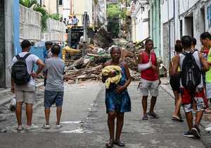 Neighbours watch as rescuers work at an apartment block following a collapse, in Havana, on October 4, 2023. At least one person has died, a firefighter, and two others are missing after the collapse at an apartment block where around fifty people were living, emergency services and state media announced on Wednesday. A woman, a member of a fire brigade who had come to the scene to secure the area after the first collapse, died during rescue operations in a second collapse, a firefighter told AFP on condition of anonymity. Another firefighter and a 76-year-old resident of the building are still missing, according to the same source, who said that only the fa�ade of the building remained. (Photo by Yamil LAGE / AFP)