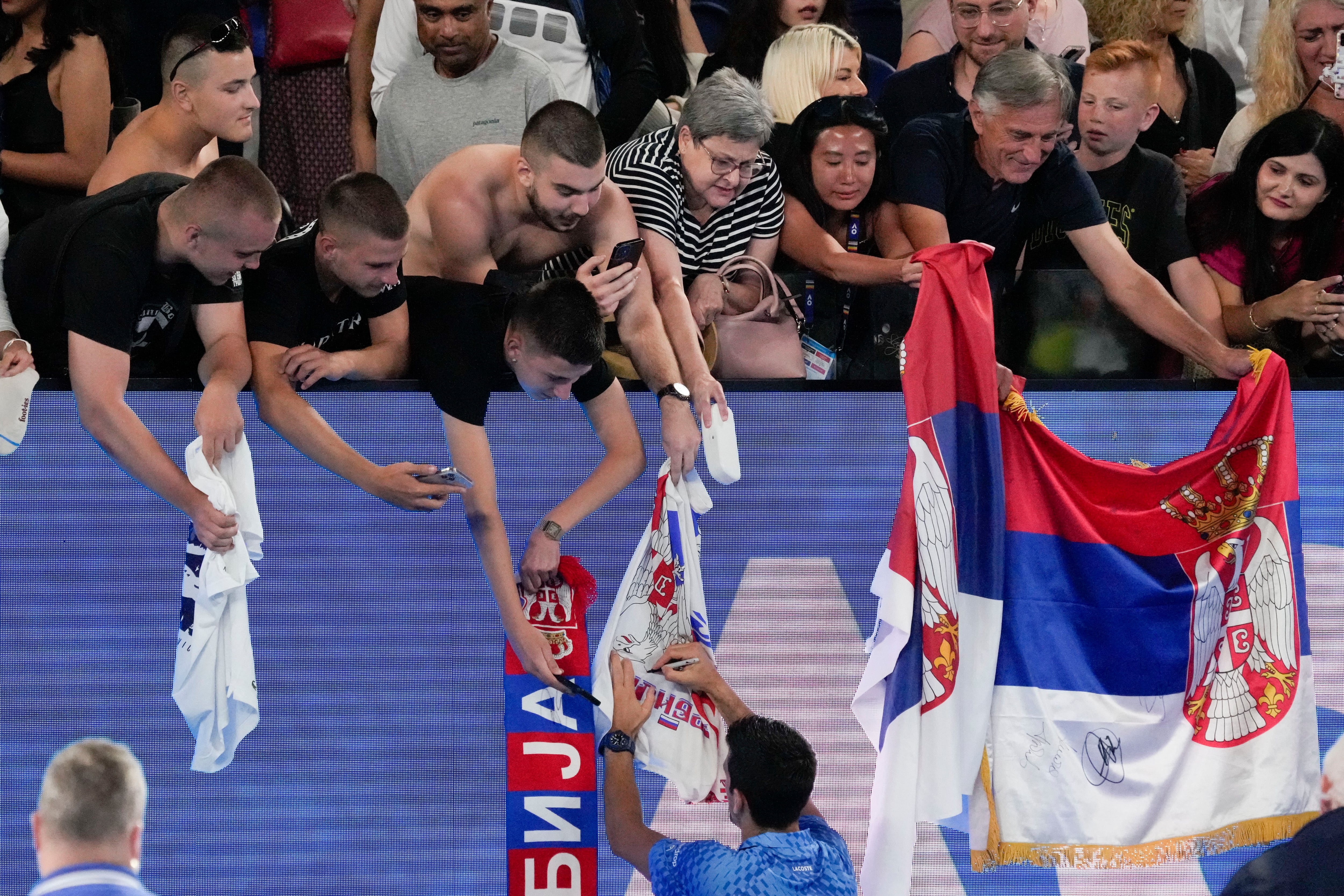 Novak Djokovic of Serbia signs autographs after defeating Roberto Carballes Baena of Spain in their first round match at the Australian Open tennis championship in Melbourne, Australia, Wednesday, Jan. 18, 2023. (AP Photo/Aaron Favila)