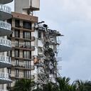 Rubble hangs from a partially collapsed building in Surfside north of Miami Beach, on June 24, 2021. - The multi-story apartment block in Florida partially collapsed early June 24, sparking a major emergency response. Surfside Mayor Charles Burkett told NBC�s Today show: �My police chief has told me that we transported two people to the hospital this morning at least and one has died. We treated ten people on the site.� (Photo by CHANDAN KHANNA / AFP)