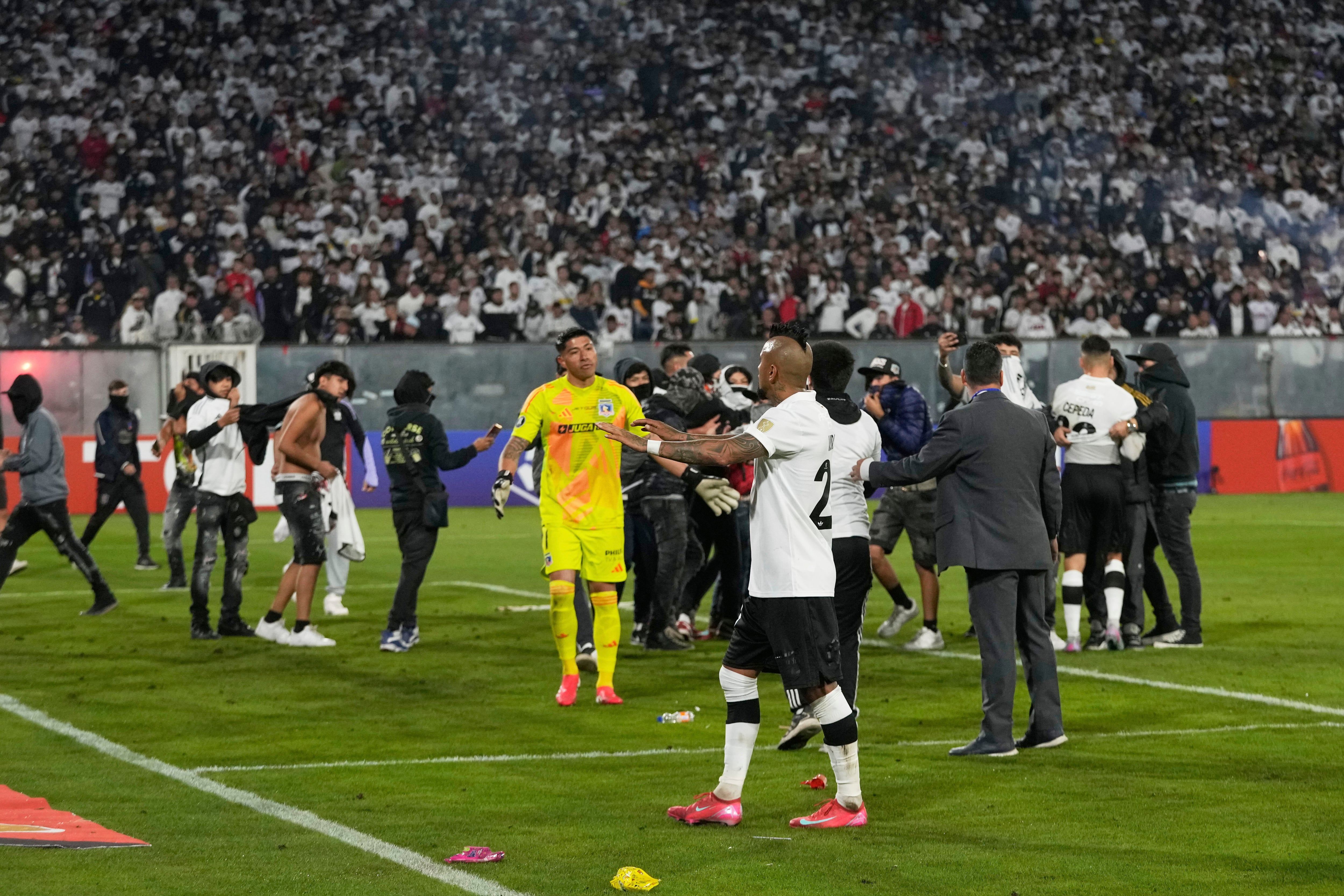 Arturo Vidal of Chile's Colo Colo talks to fans who invaded the field during a Copa Libertadores Group E soccer match between Chile's Colo Colo and Brazil's Fortaleza at the Monumental stadium in Santiago, Chile, Thursday, April 10, 2025. (AP Photo/Esteban Felix)