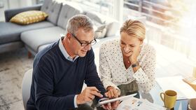 Shot of a mature couple using a digital tablet while going through paperwork at home