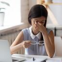 Exhausted young Caucasian woman work on laptop take off glasses suffer from blurry vision or dizziness. Tired millennial female employee struggle with headache or migraine, have eyesight problems.