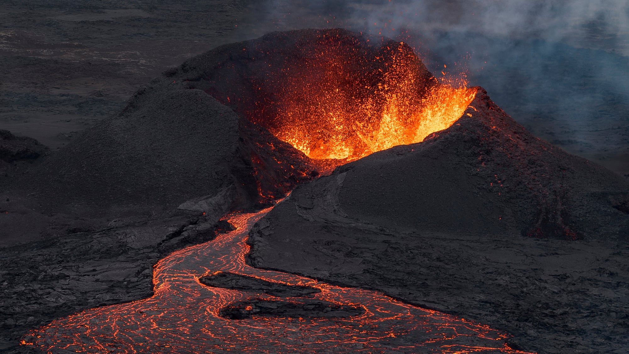 Se ve un flujo de lava en la base del cráter, de fondo, que todavía está muy activo después de una erupción volcánica a unos 6 km al norte de Grindavik en la península de Reykjanes, en Islandia. Miércoles 23 de julio de 2025.