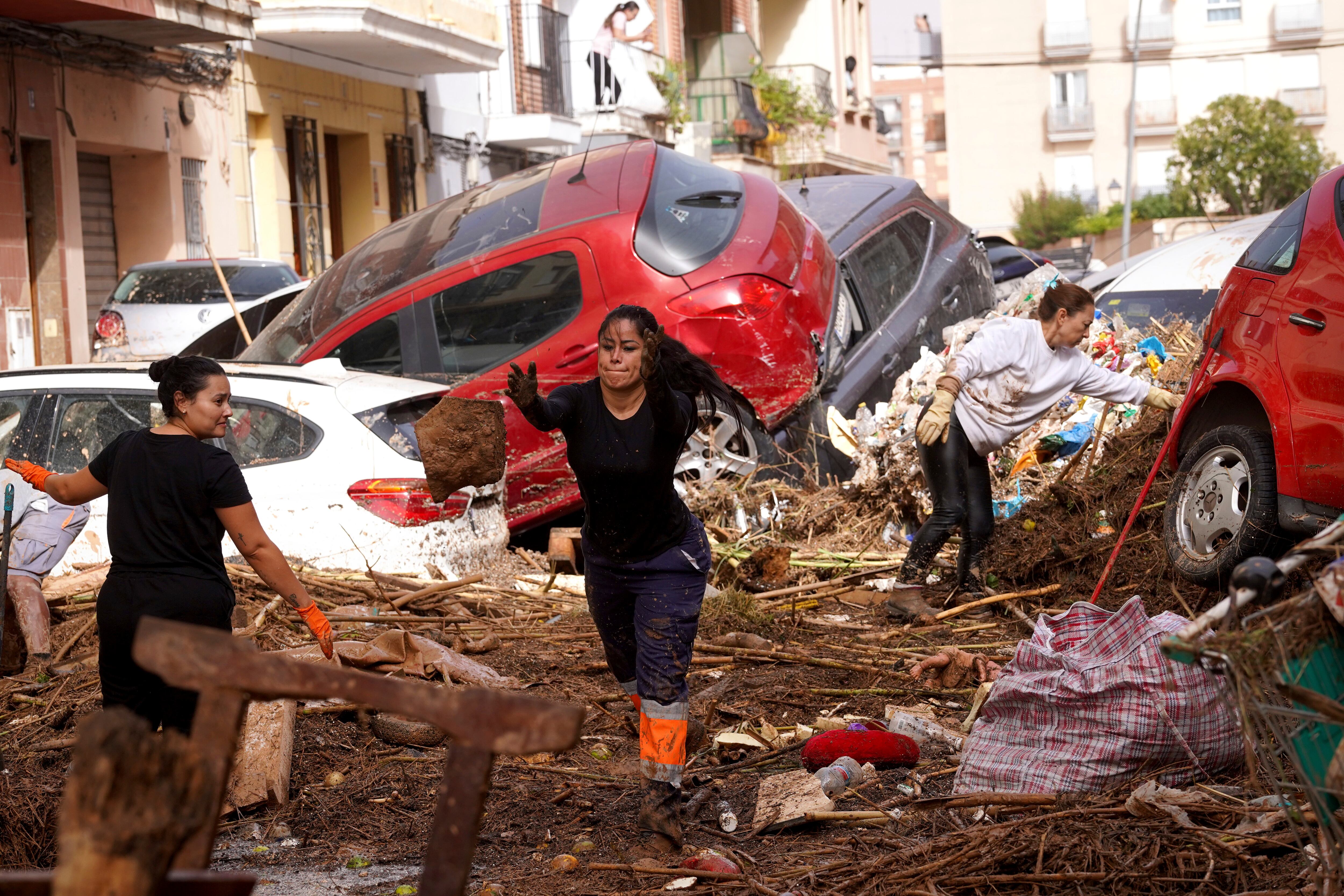 Los residentes limpian la calle junto a los autos amontonados después de ser arrastrados por las inundaciones en Valencia, España, el miércoles 30 de octubre de 2024. (Foto AP/Alberto Saiz)