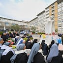 Fieles, monjas y sacerdotes rezan ante la estatua de Juan Pablo II en el exterior del Hospital Universitario Gemelli, donde el Papa Francisco está hospitalizado por neumonía, en Roma, el 9 de marzo de 2025 (Foto de ANDREAS SOLARO / AFP o licenciante / AFP)