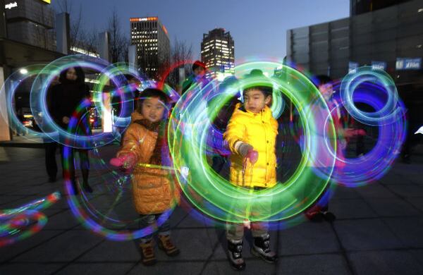Niños hacen girar las luces de colores que traen sus juguetes como parte de la celebración de la primera luna llena en el calendario de Corea del Sur. (AP)