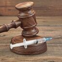 Judges Gavel And Syringe Or Injection On Brown Wooden Table Background Close-up, Front View