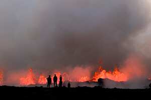 People watch flowing lava during an volcanic eruption near Litli Hrutur, south-west of Reykjavik in Iceland on July 10, 2023. A volcanic eruption started on July 10, 2023 around 30 kilometres (19 miles) from Iceland's capital Reykjavik, the country's meteorological office said, marking the third time in two years that lava has gushed out in the area. "The eruption is taking place in a small depression just north of Litli Hrutur, from which smoke is escaping in a north-westerly direction," the office said. Footage circulating in the local media shows a massive cloud of smoke rising from the ground as well as a substantial flow of lava. (Photo by Kristinn Magnusson / AFP) / Iceland OUT