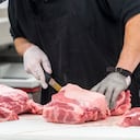 carnicero masculino irreconocible preparando carne cruda supermercado