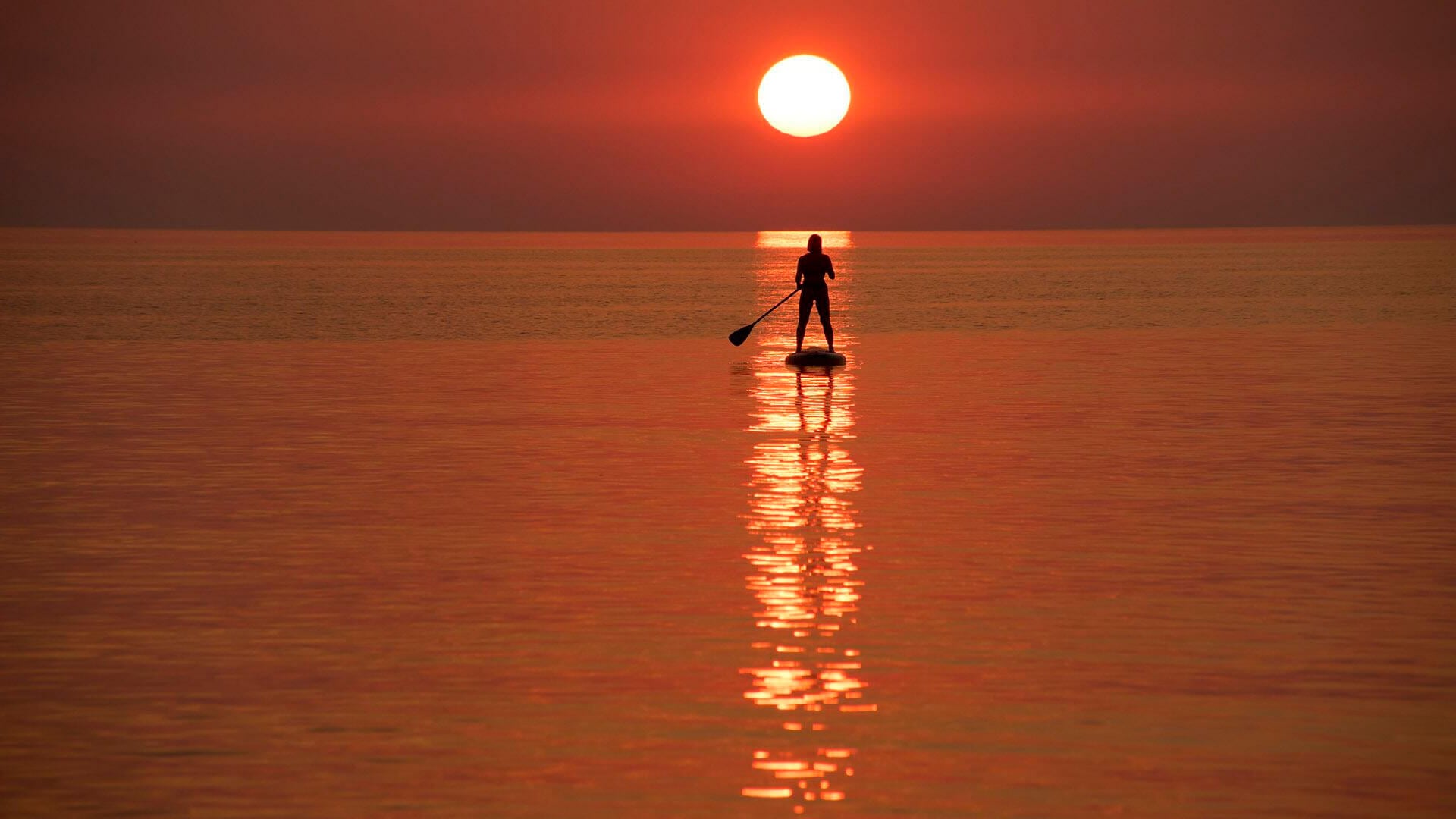 Un veraneante dirige un stand-up paddleboard al atardecer fuera de la orilla del mar en Yantarny, un pueblo turístico en la península de Sambia en la región de Kaliningrado al oeste de Rusia, el miércoles 5 de agosto de 2026.