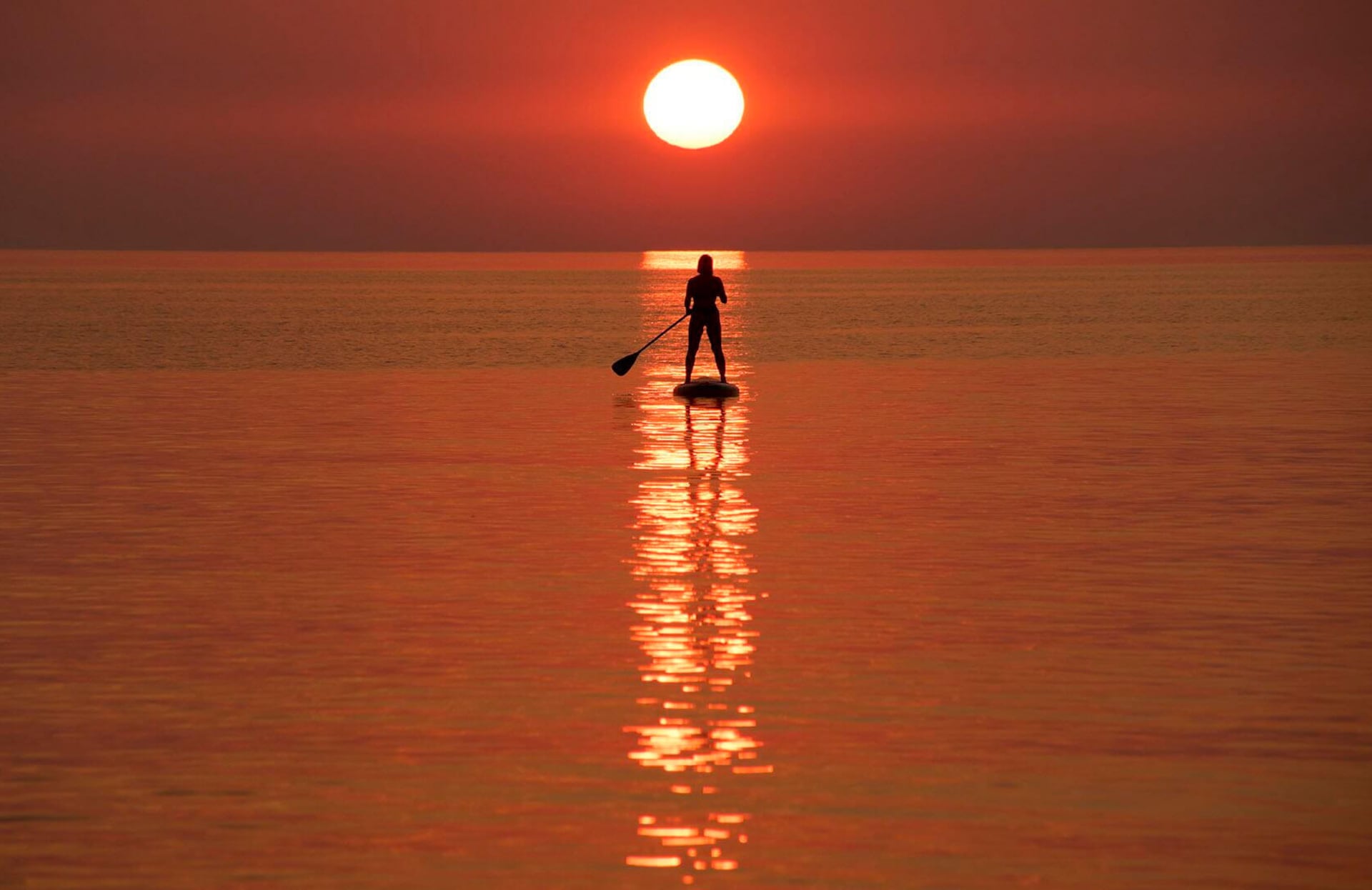 Un veraneante dirige un stand-up paddleboard al atardecer fuera de la orilla del mar en Yantarny, un pueblo turístico en la península de Sambia en la región de Kaliningrado al oeste de Rusia, el miércoles 5 de agosto de 2026.