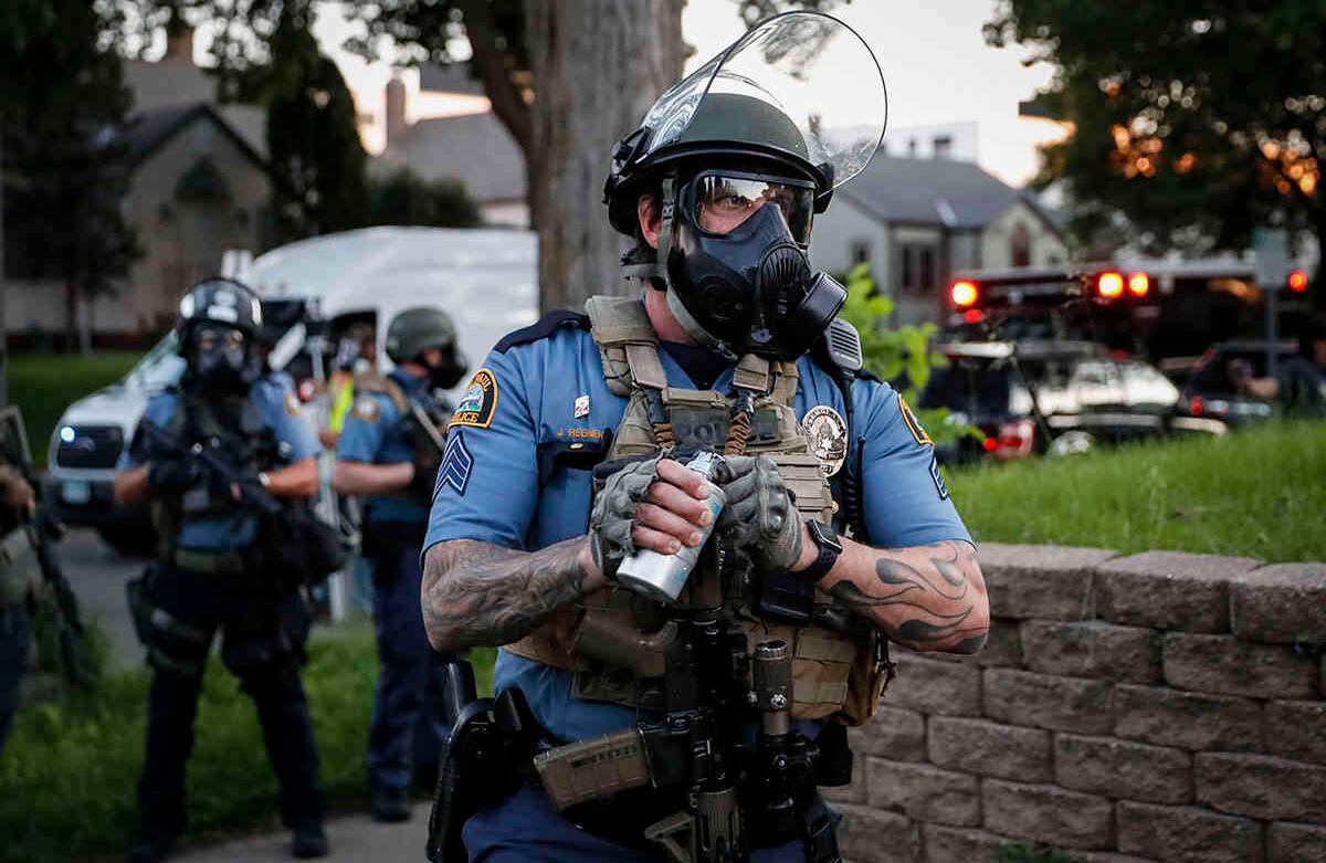 Un oficial de policía se prepara para lanzar un bote de gas lacrimógeno contra los manifestantes, el jueves 28 de mayo de 2020, en St. Paul, Minnesota. (Foto AP / John Minchillo)