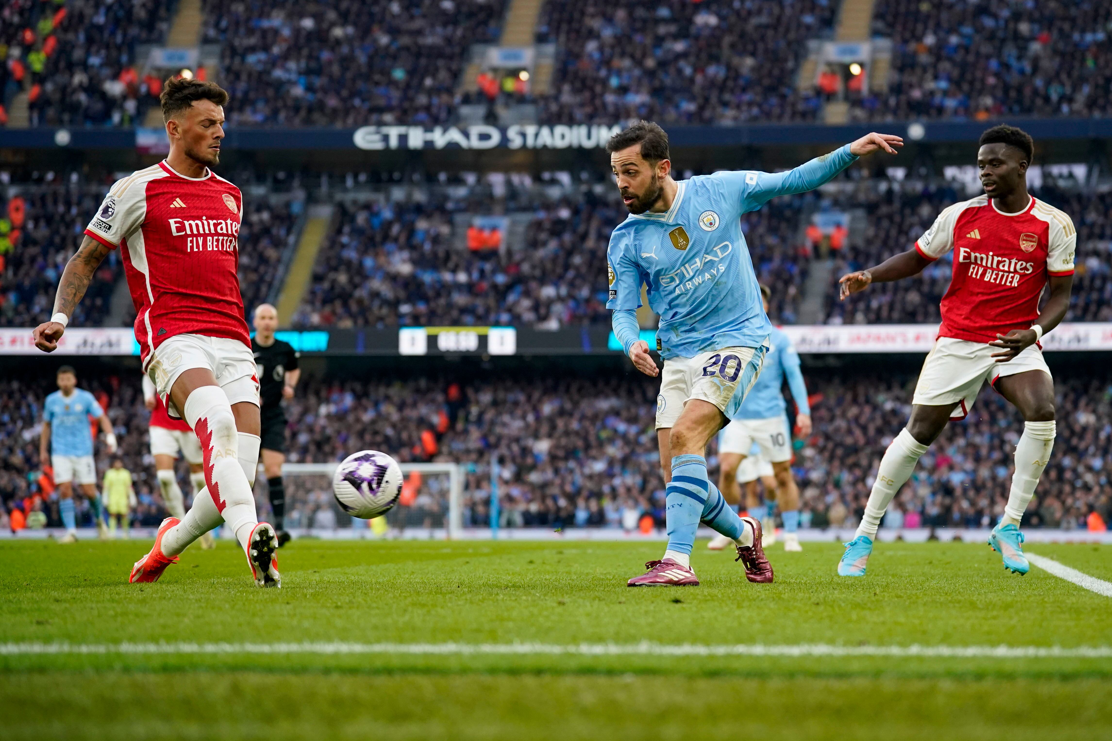 Arsenal's Ben White, left, tries to block a shot from Manchester City's Bernardo Silva during the English Premier League soccer match between Manchester City and Arsenal at the Etihad stadium in Manchester, England, Sunday, March 31, 2024. (AP Photo/Dave Thompson