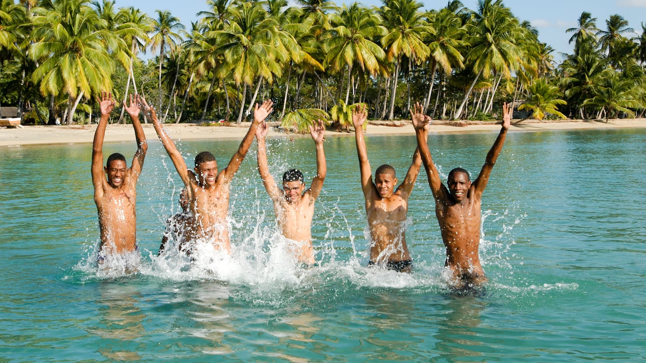 Jóvenes saltando del agua en la playa de Punta El Rey en Costa Esmeralda, República Dominicana.