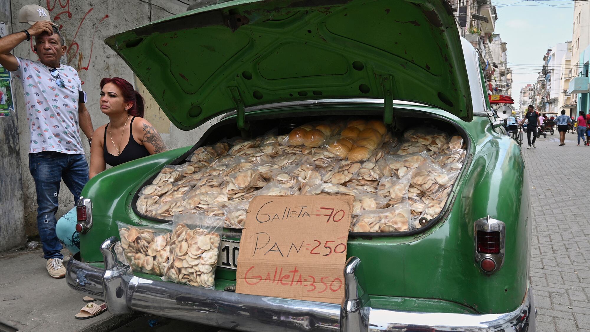 Los vendedores esperan a los clientes junto al maletero de su coche clásico americano relleno de patatas fritas caseras y pan, en La Habana, Cuba. Martes 15 de julio de 2025.