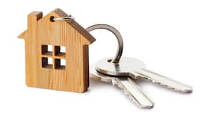 Llaves de casa con llavero en forma de casa, aislado sobre fondo blanco.