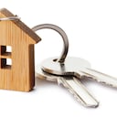 Llaves de casa con llavero en forma de casa, aislado sobre fondo blanco.