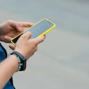 Manos de hombre recogiendo un teléfono celular para usar la aplicación uber y solicitar un servicio de transporte