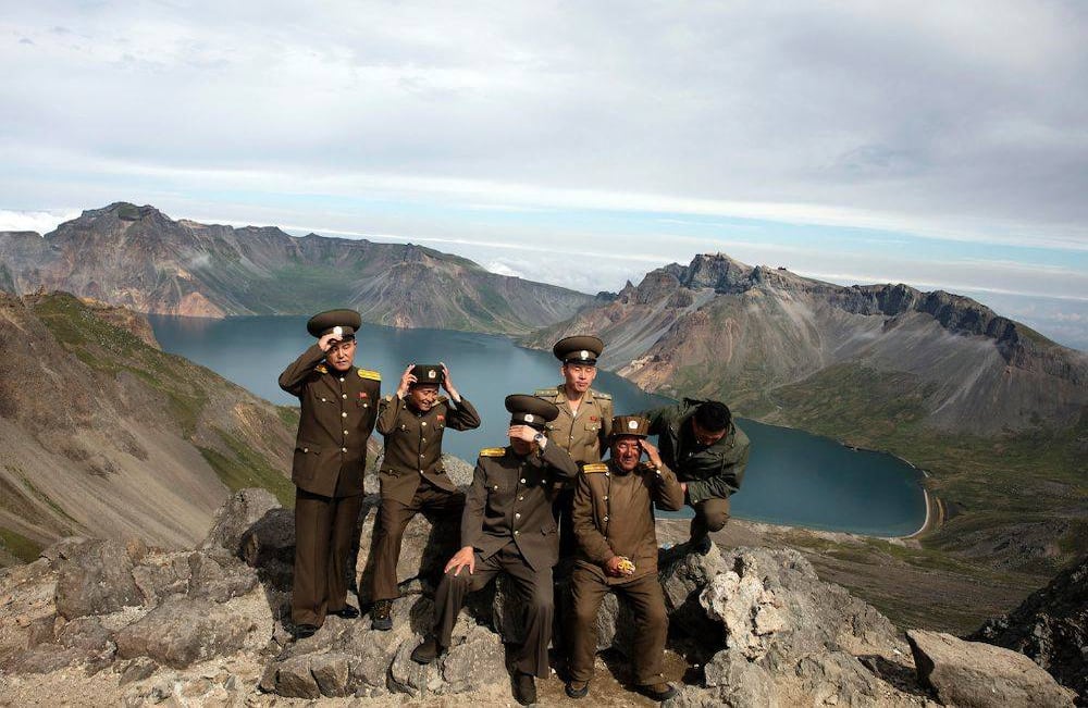 Los soldados norcoreanos se ajustan sus sombreros antes de posar para una foto en un mirador con vista a la caldera del Monte Paektu en Corea del Norte, el sábado 18 de agosto de 2018. (AP Photo / Ng Han Guan)