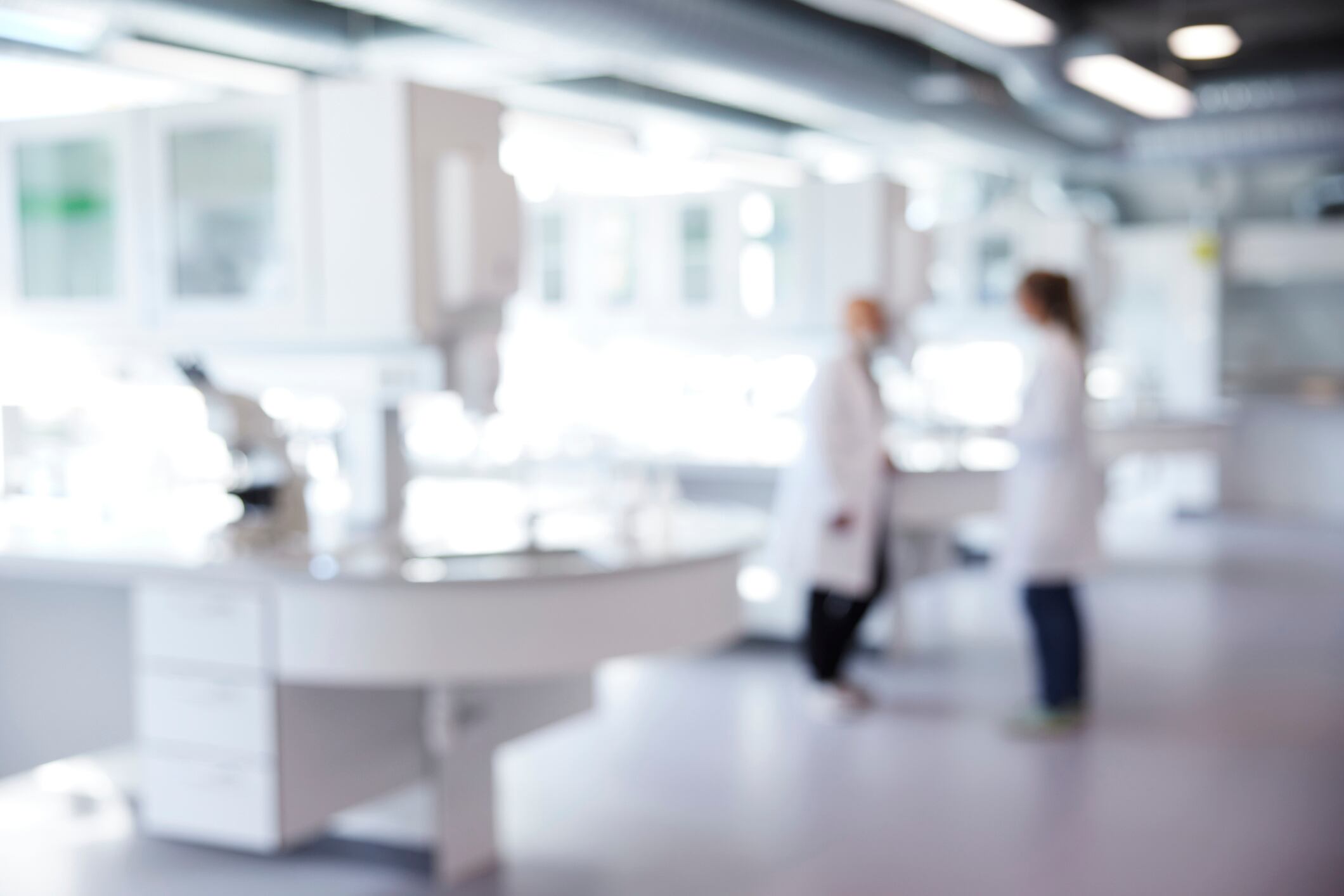 Imagen desenfocada de laboratorio con dos científicas dentro de un hospital
