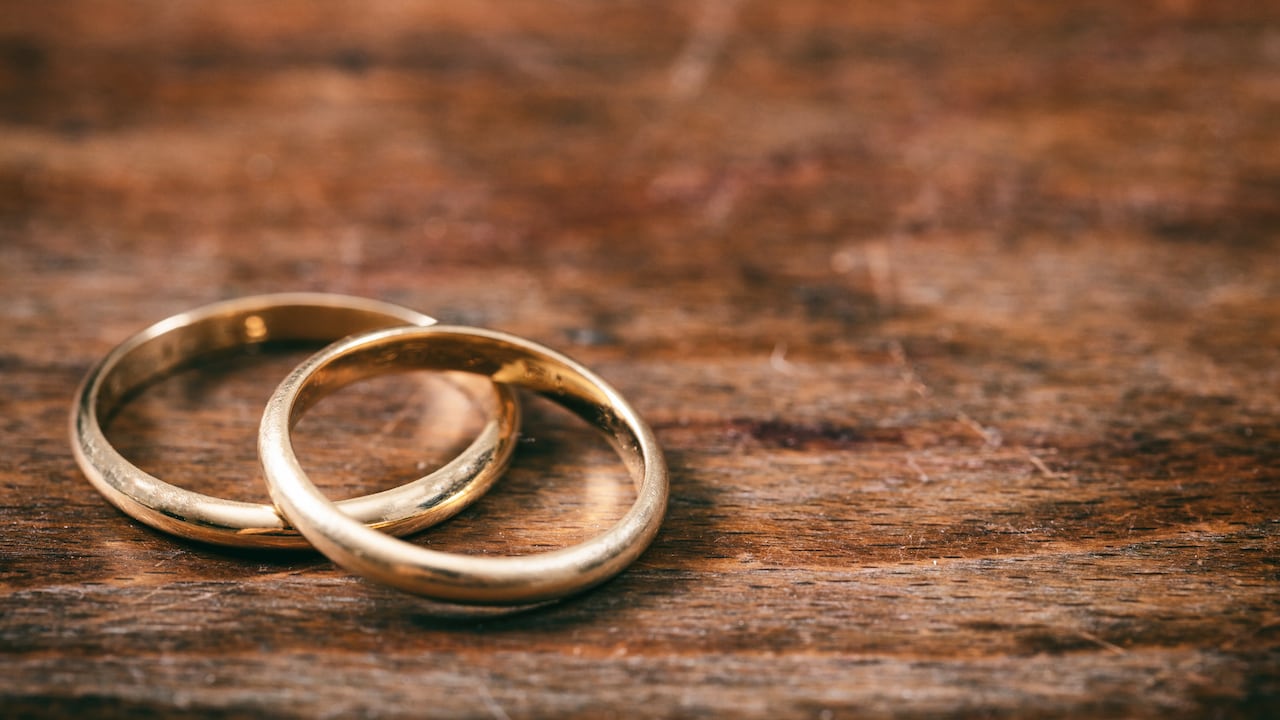 Un par de anillos de bodas de oro sobre fondo de madera, espacio de copia
