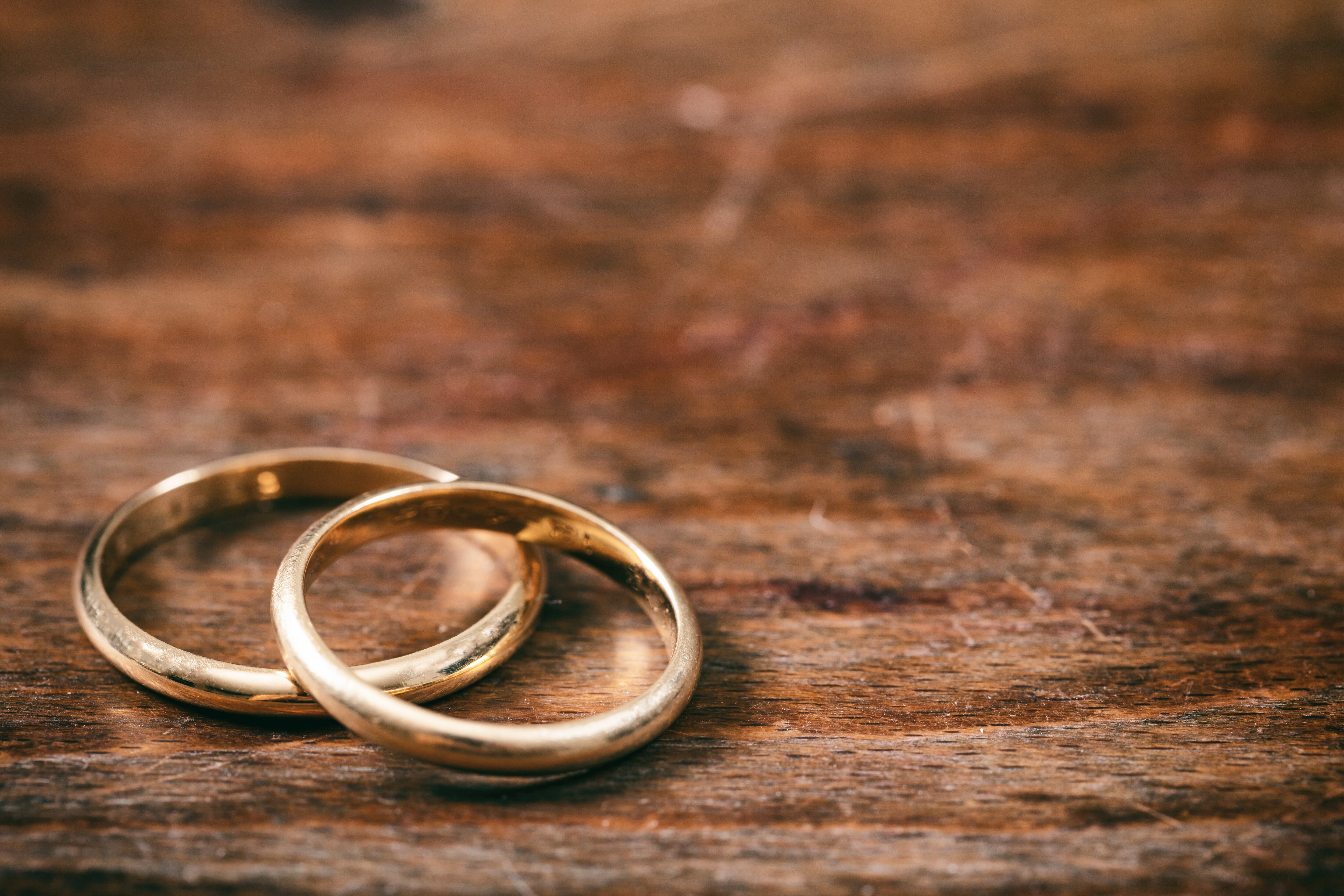 Un par de anillos de bodas de oro sobre fondo de madera, espacio de copia