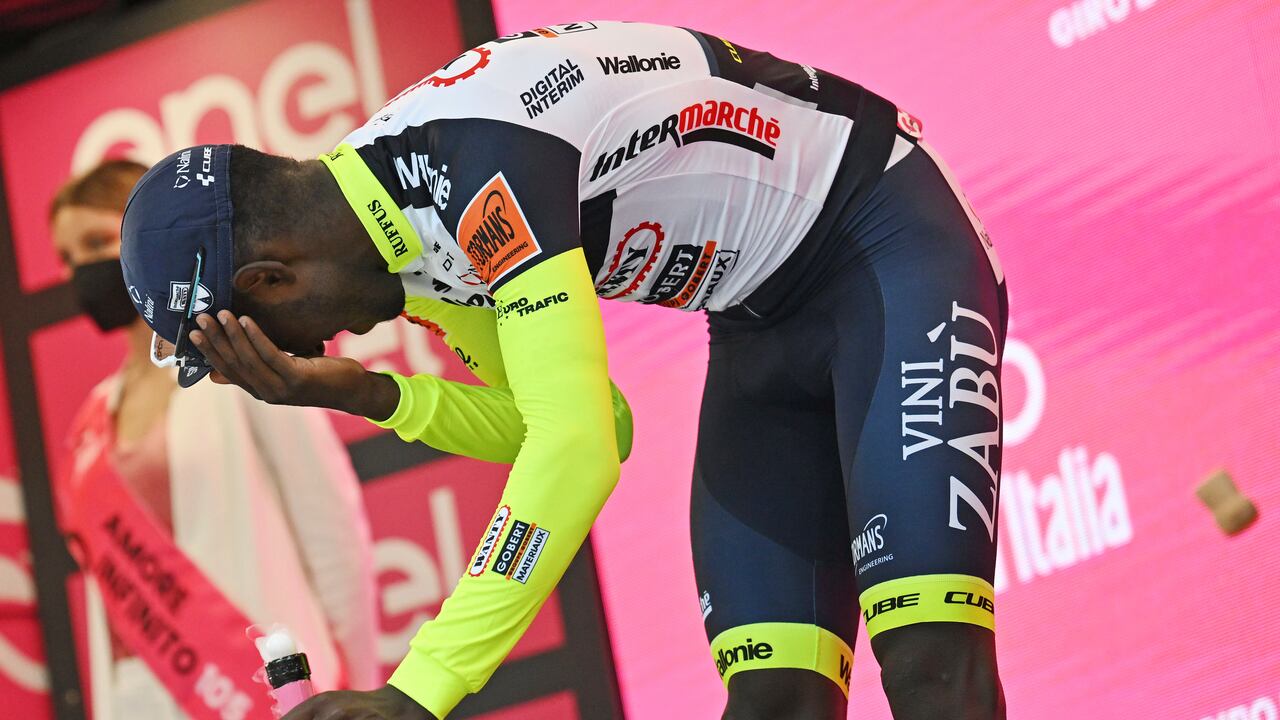 Eritrea's Biniam Girmay touches his eye after spraying sparkling wine on the podium to celebrate winning the 10th stage of the Giro D'Italia cycling race from Pescara to Jesi, Italy, Tuesday, May 17, 2022. Girmay was then taken to a local hospital after getting injured when he popped a champagne cork into his eye during the podium celebration. (Massimo Paolone/LaPresse via AP)