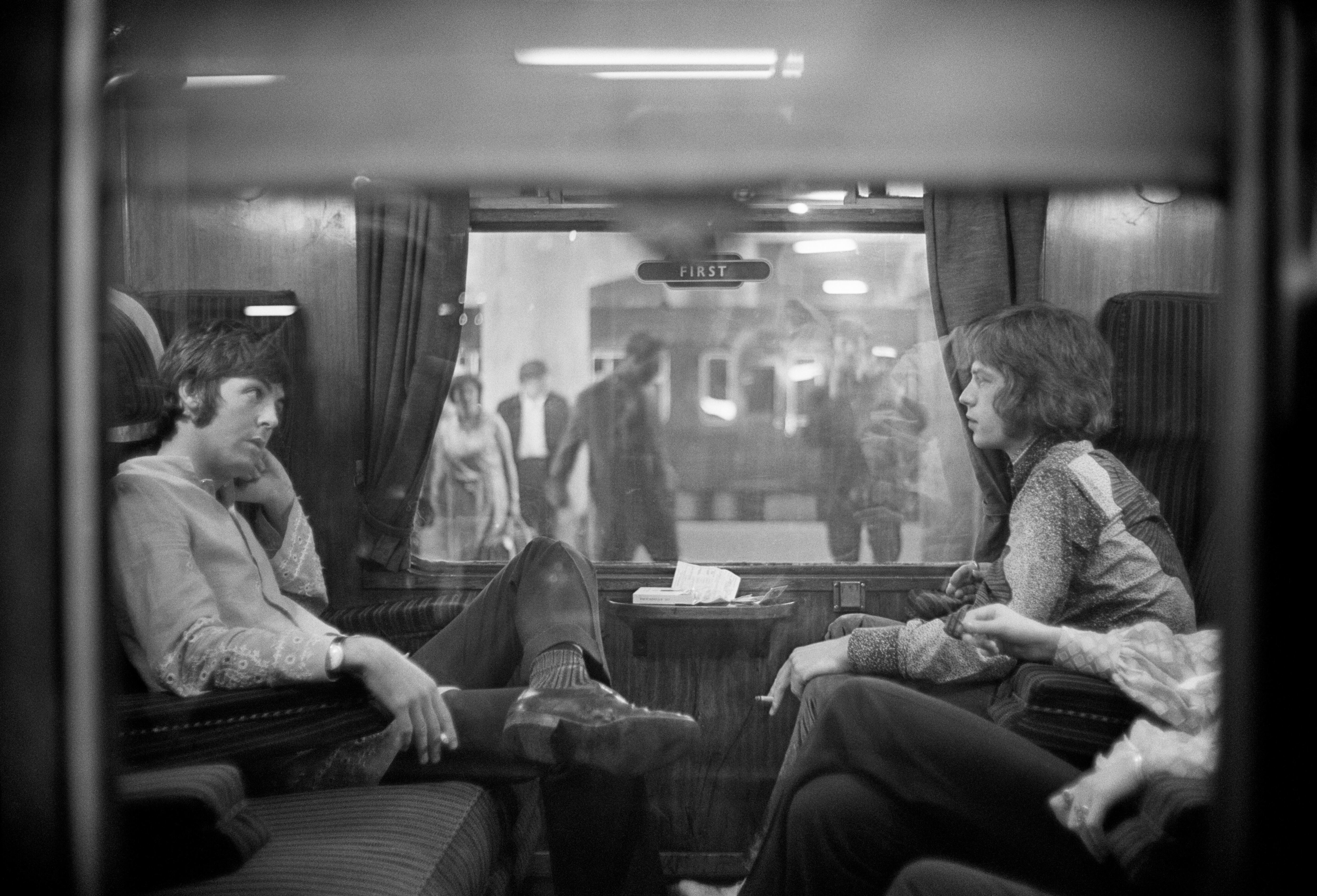 25th August 1967:  Paul McCartney of the Beatles and Mick Jagger of the Rolling Stones sit opposite each other on a train at Euston Station, waiting for departure to Bangor.  (Photo by Victor Blackman/Express/Getty Images)