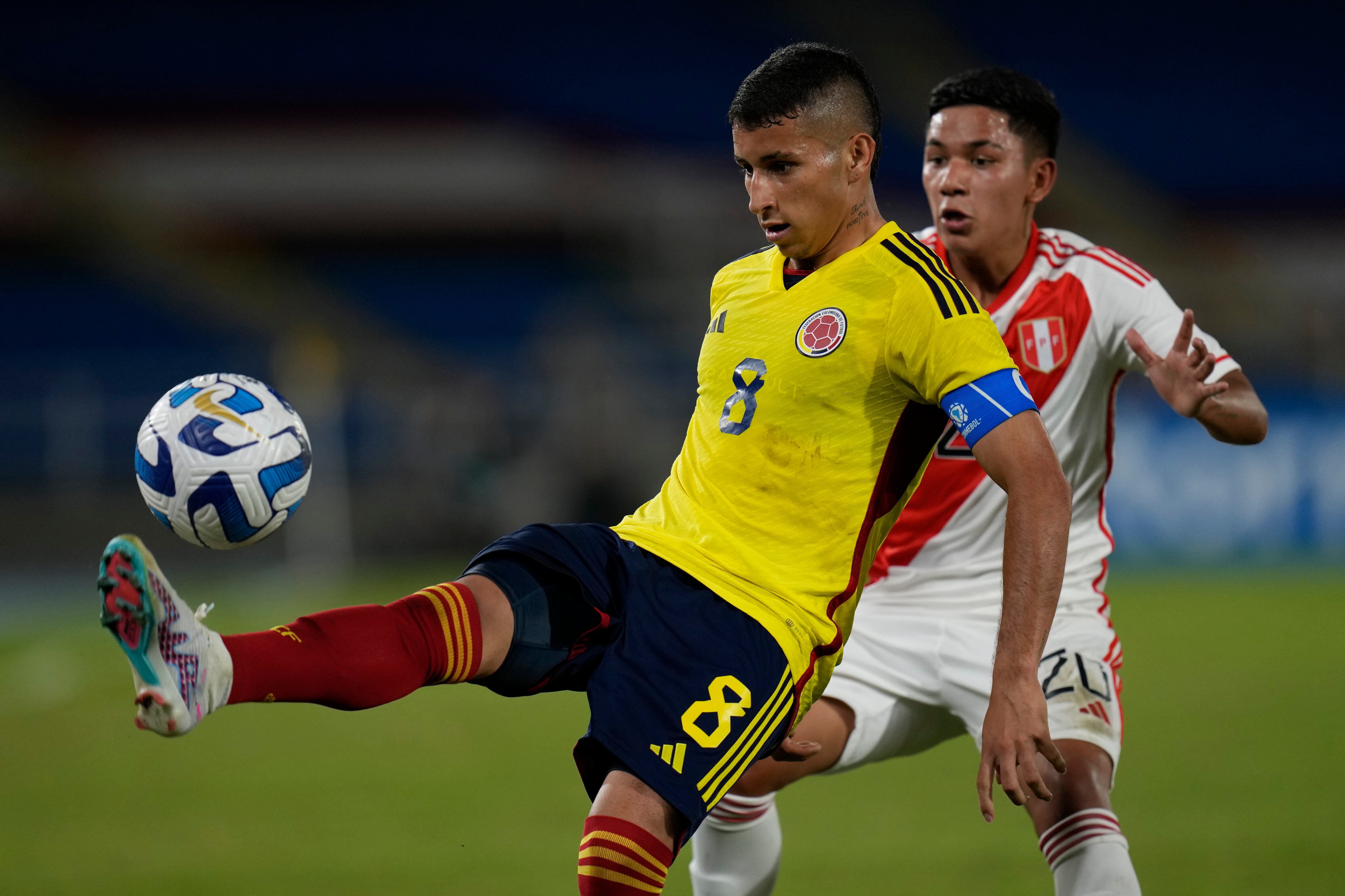 Colombia's Gustavo Puerta, left, fight for the ball with Peru's Lisardo Vasquez during a South America U-20 soccer match in Cali, Colombia, Saturday, Jan. 21, 2023. (AP Photo/Fernando Vergara)