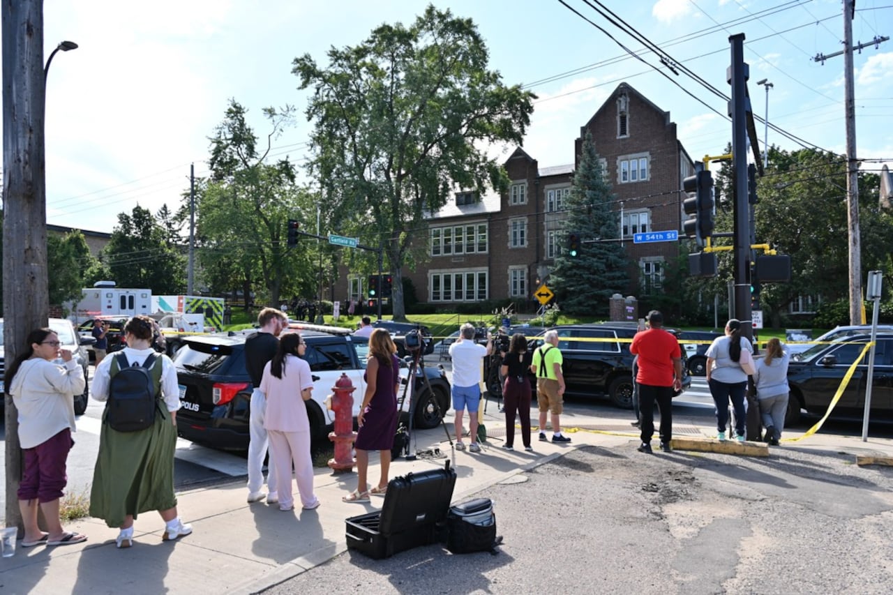 Transeúntes y medios de comunicación observan cerca del lugar del tiroteo en la Escuela Católica Annunciation en Minneapolis, Minnesota, el 27 de agosto de 2025. Dos niños murieron a tiros cuando un hombre armado atacó una iglesia de Minneapolis el miércoles, dejando 17 heridos, 14 de ellos niños, según informó la policía.