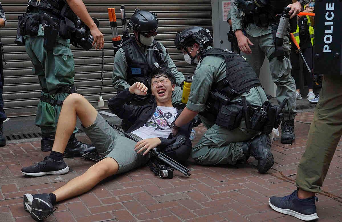 Un periodista cae después de ser rociado con gas pimienta por la policía durante una protesta en Causeway Bay durante la marcha anual de entrega en Hong Kong. Foto: Vincent Yu/AP