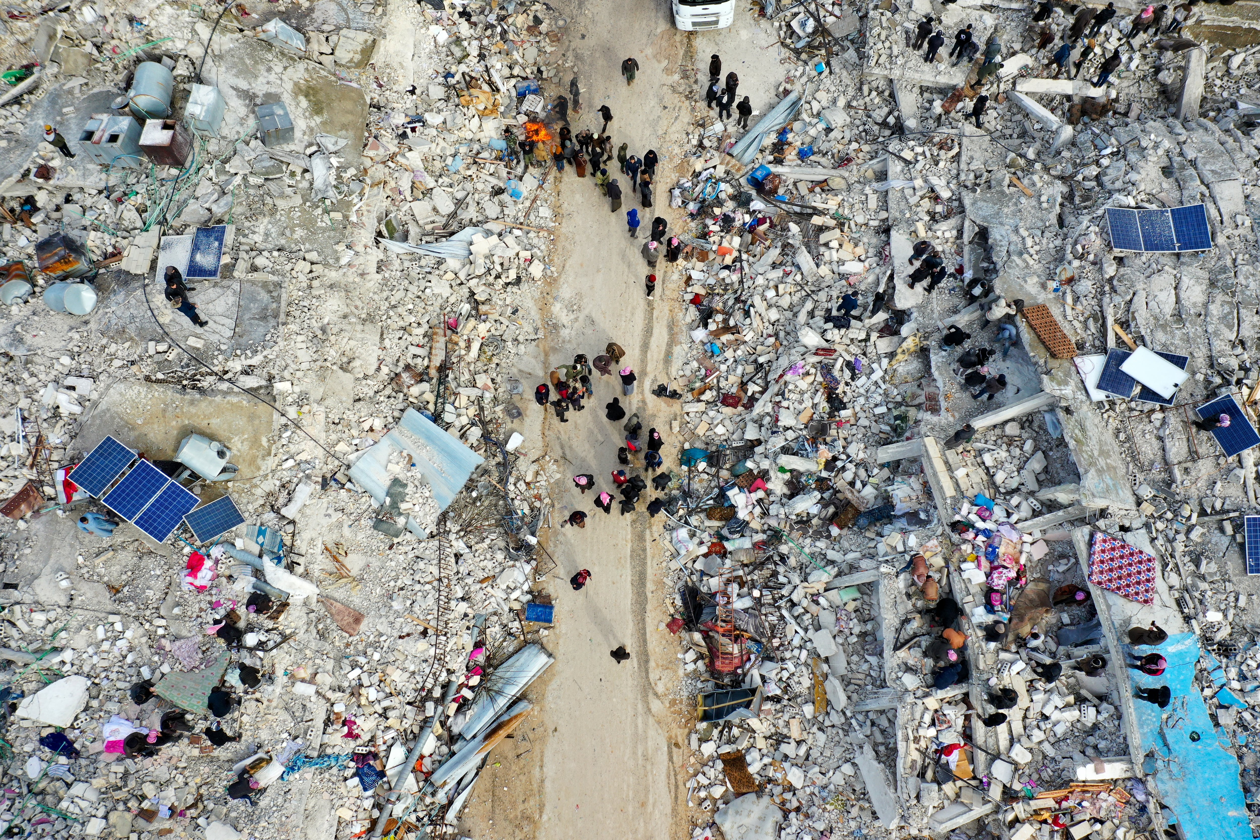 This aerial view shows residents searching for victims and survivors amidst the rubble of collapsed buildings following an earthquake in the village of Besnia near the town of Harim, in Syria's rebel-held noryhwestern Idlib province on the border with Turkey, on February 6, 2022. - Hundreds have been reportedly killed in north Syria after a 7.8-magnitude earthquake that originated in Turkey and was felt across neighbouring countries. (Photo by Omar HAJ KADOUR / AFP)
