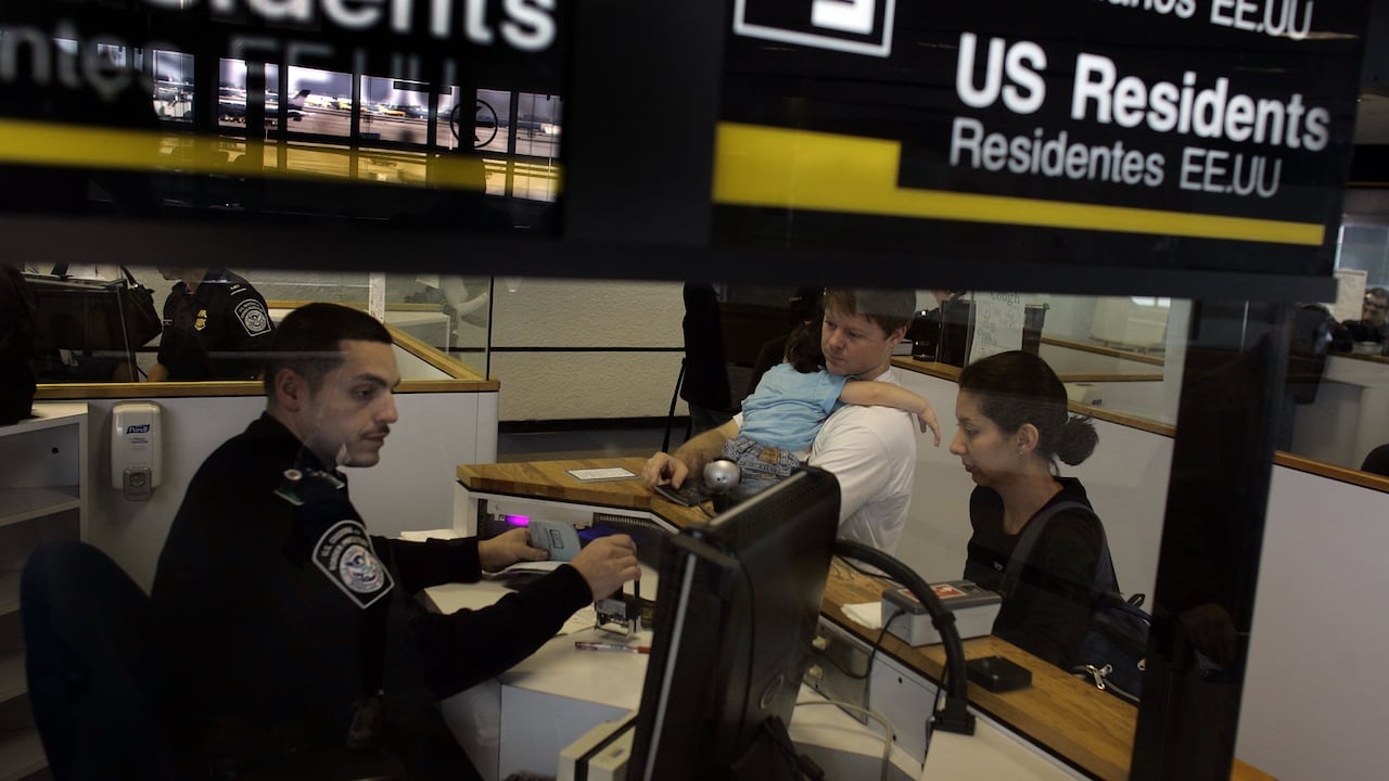Oficial de Aduanas y Protección Fronteriza, revisa documentación de viajeros en un aeropuerto