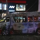 Personas observan un vehículo de transporte quemado tras ser incendiado por individuos no identificados en Tijuana, estado de Baja California, México, el 12 de agosto de 2022. Varios vehículos fueron incendiados, ese mismo día, en la ciudad. (Photo by Guillermo Arias / AFP)