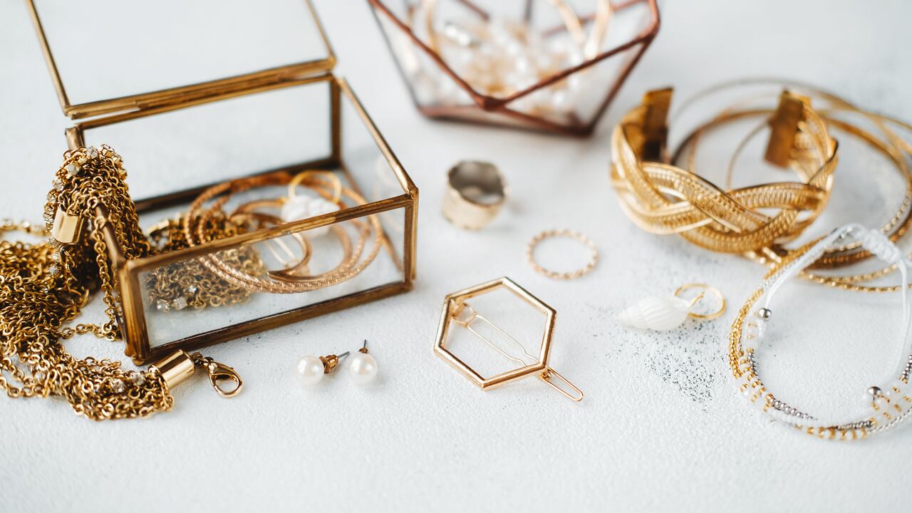 Various pearl and gold jewelry in glass boxes and on white surface.