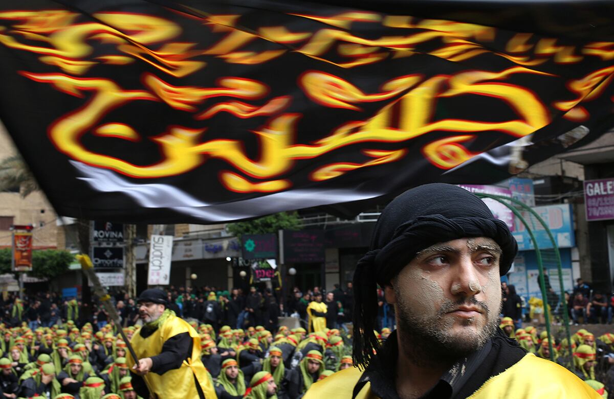 Un chiíta libanés con lodo en su cara y otro ondeando una bandera participan en la celebración de Ashura, una festividad religiosa islámica. (AP) 