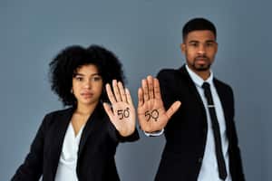 Shot of businessman and businesswoman advocating for gender equality against a grey studio background