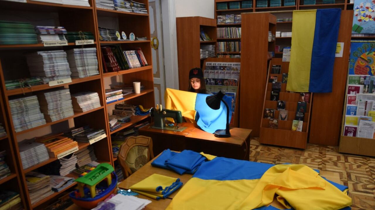 Un joven voluntario cose banderas ucranianas para el ejército ucraniano en una biblioteca en la ciudad de Lviv, en el oeste de Ucrania, el 2 de abril de 2022. (Foto de Yuriy Dyachyshyn / AFP)