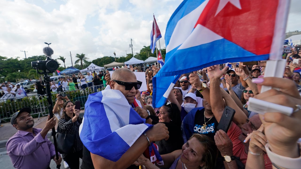Envuelto en una bandera cubana, el músico de reguetón cubano Alexander Delgado, a la izquierda, con la banda Gente de Zona, saluda a la multitud. La canción de Gente de Zona "Patria y Vida", que significa Patria y Vida, se ha convertido en el himno de las manifestaciones y es una obra de teatro con la frase "Patria o Muerte", Patria o muerte, que era una frase en la Revolución Cubana. (Foto AP / Wilfredo Lee)