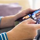 Enfoque selectivo en la mano de los hombres y la tableta digital. Hombre asiático adulto joven que sostiene un dispositivo de tableta mientras elige la aplicación de transmisión de películas en línea con red inalámbrica móvil en casa. Concepto de entretenimiento.