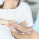 On bed lies a sick doctor sitting next to him and sympathetically holds hand. Euthanasia in world practice concept