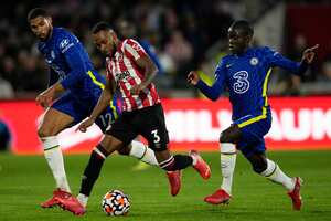 Brentford's Rico Henry runs with the ball between Chelsea's Ruben Loftus-Cheek, left, and N'Golo Kante, right, during the English Premier League soccer match between Brentford and Chelsea at Brentford Community Stadium in London, Saturday, Oct. 12, 2021. (AP Photo/Matt Dunham)