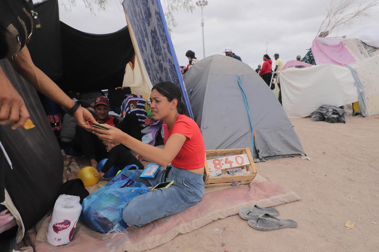 Una familia venezolana espera información para ingresar a Perú, en Arica, en la frontera entre Chile y Perú, el 4 de mayo de 2023. - Un primer vuelo de repatriación para cientos de migrantes venezolanos varados en la frontera con Perú tras el endurecimiento de los controles migratorios, llegarán a Chile la madrugada del domingo, afirmó el canciller chileno, Alberto van Klaveren. El vuelo, enviado por el gobierno venezolano, aterrizará en la ciudad de Arica, para recoger a los migrantes que esperan del lado chileno en el paso fronterizo de Chacalluta y otro grupo en la ciudad peruana de Tacna. (Foto de AGUSTÍN MERCADO / AFP)